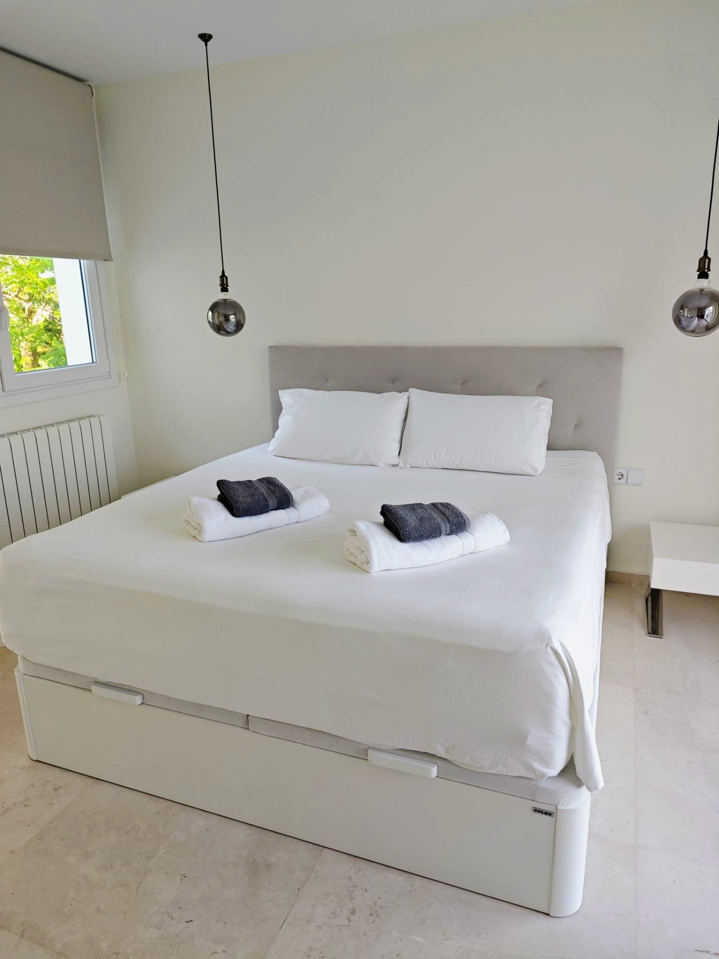 Master bedroom with upholstered headboard, pendant lights and garden window