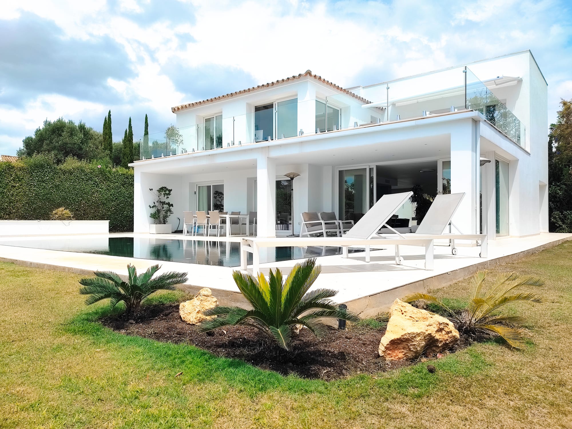 Side elevation of the villa with double-height glazing and garden