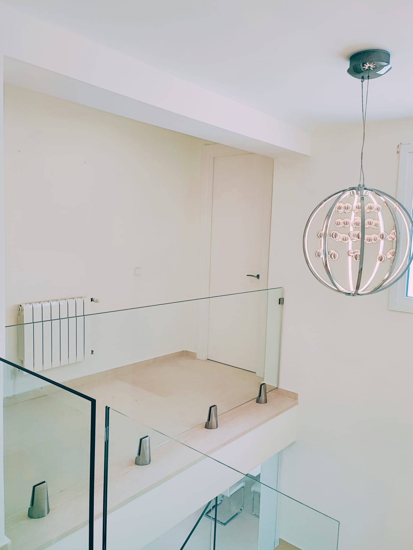 Upper landing with glass balustrade and statement spherical chandelier